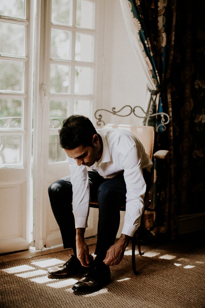 The groom gets ready by a French window