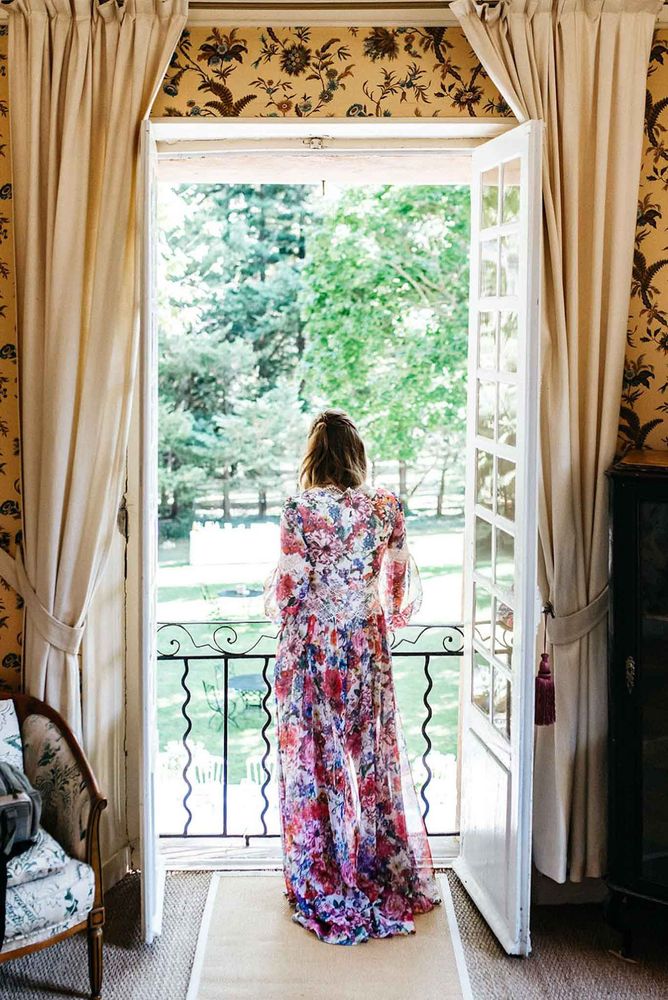 A guest at a French window open onto the park, floral curtains