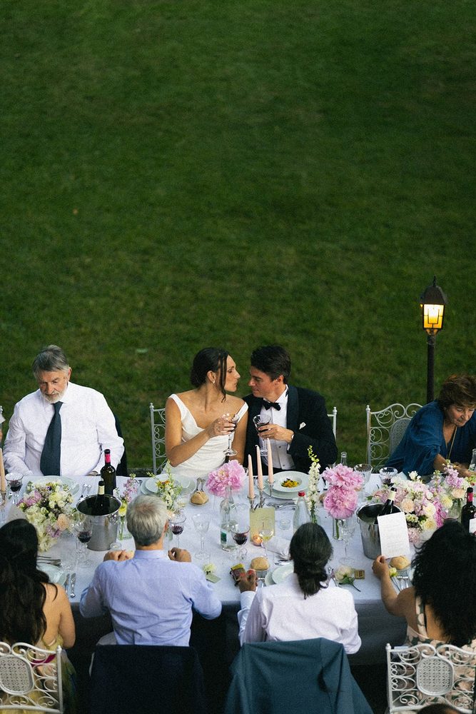 The newlyweds raise a glass at the head table, facing the lawn