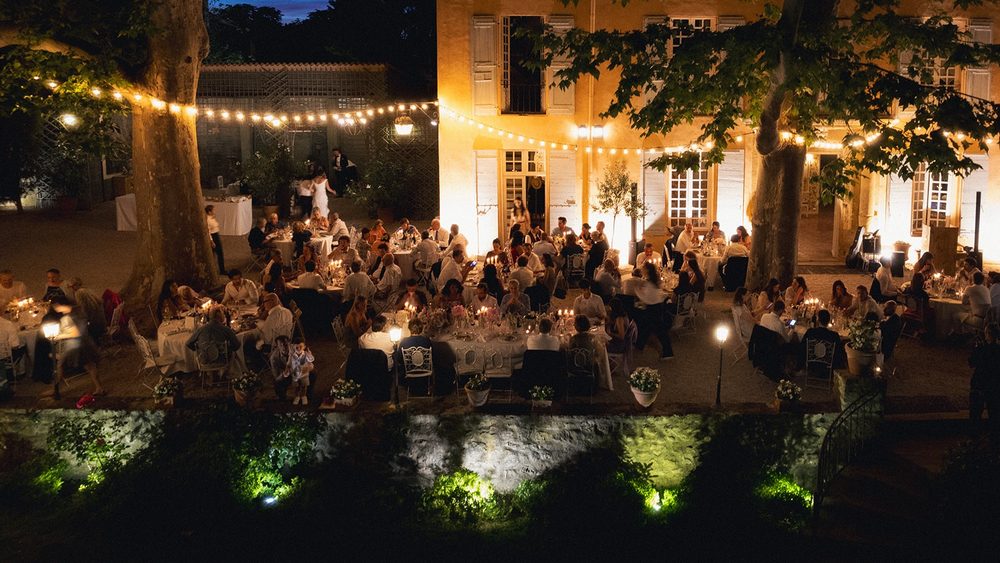 Candlelit dinner before the illuminated façade, under string lights
