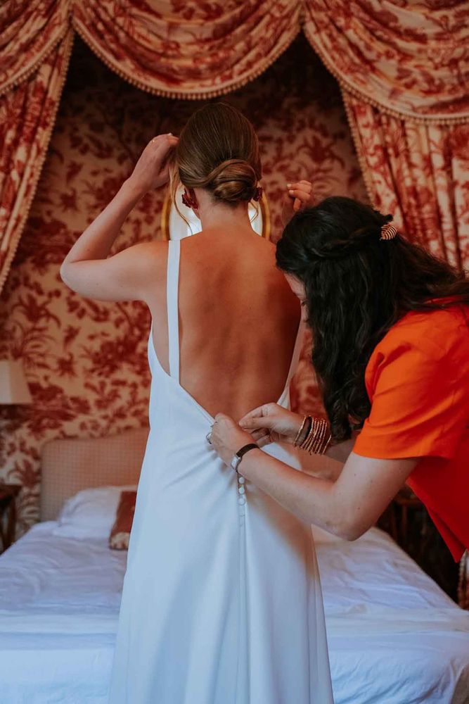 The bride gets ready in the Toile de Jouy suite, helped by a friend