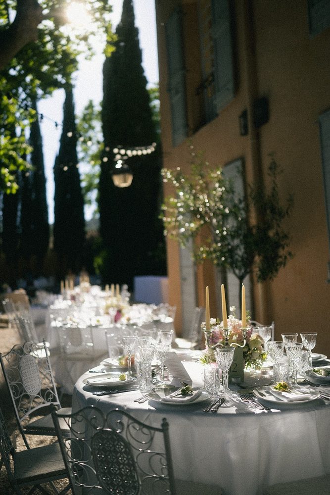 A round table laid with crystal and candles, at the foot of the cypresses